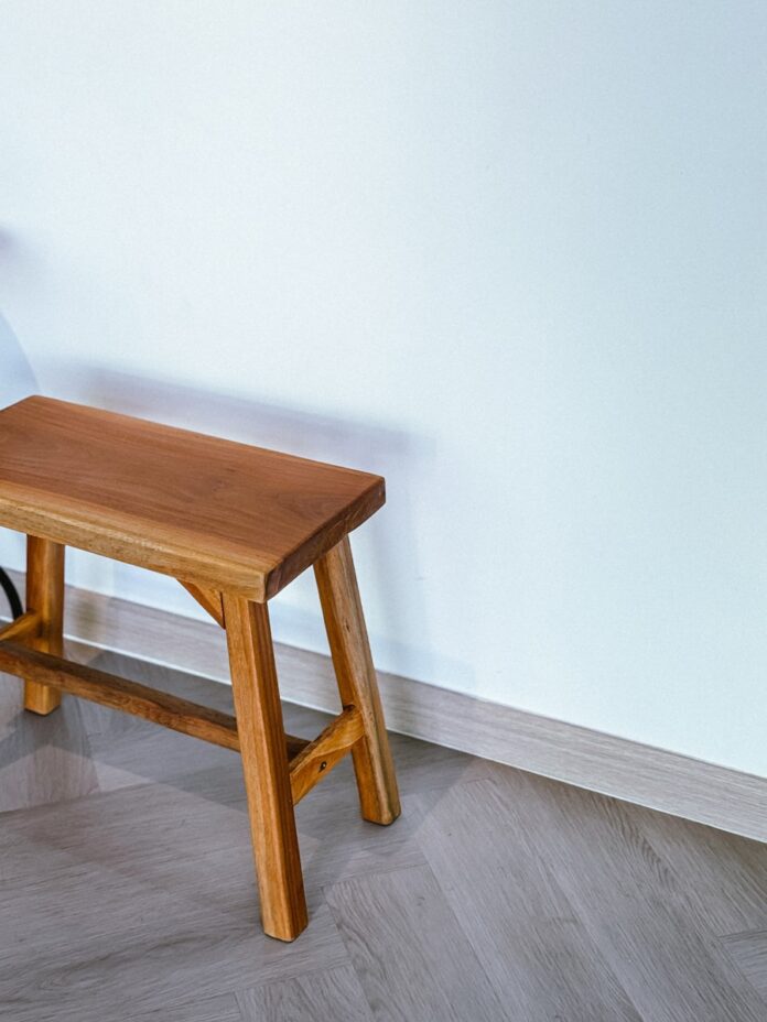 A small wooden stool sitting on top of a hard wood floor