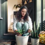 바쁜 일상 속, 스트레스 관리의 새로운 해법을 찾다 Woman potting a plant on a porch